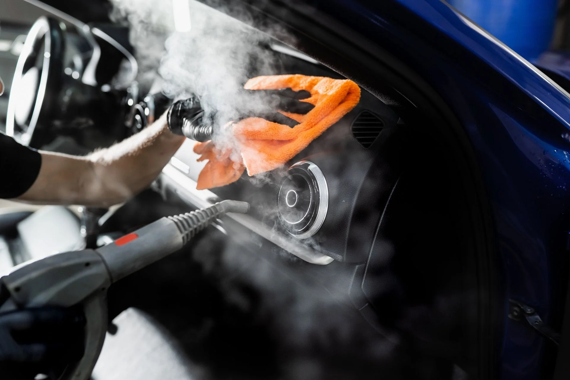 Professional car detailing with steam cleaning interior dashboard and vents