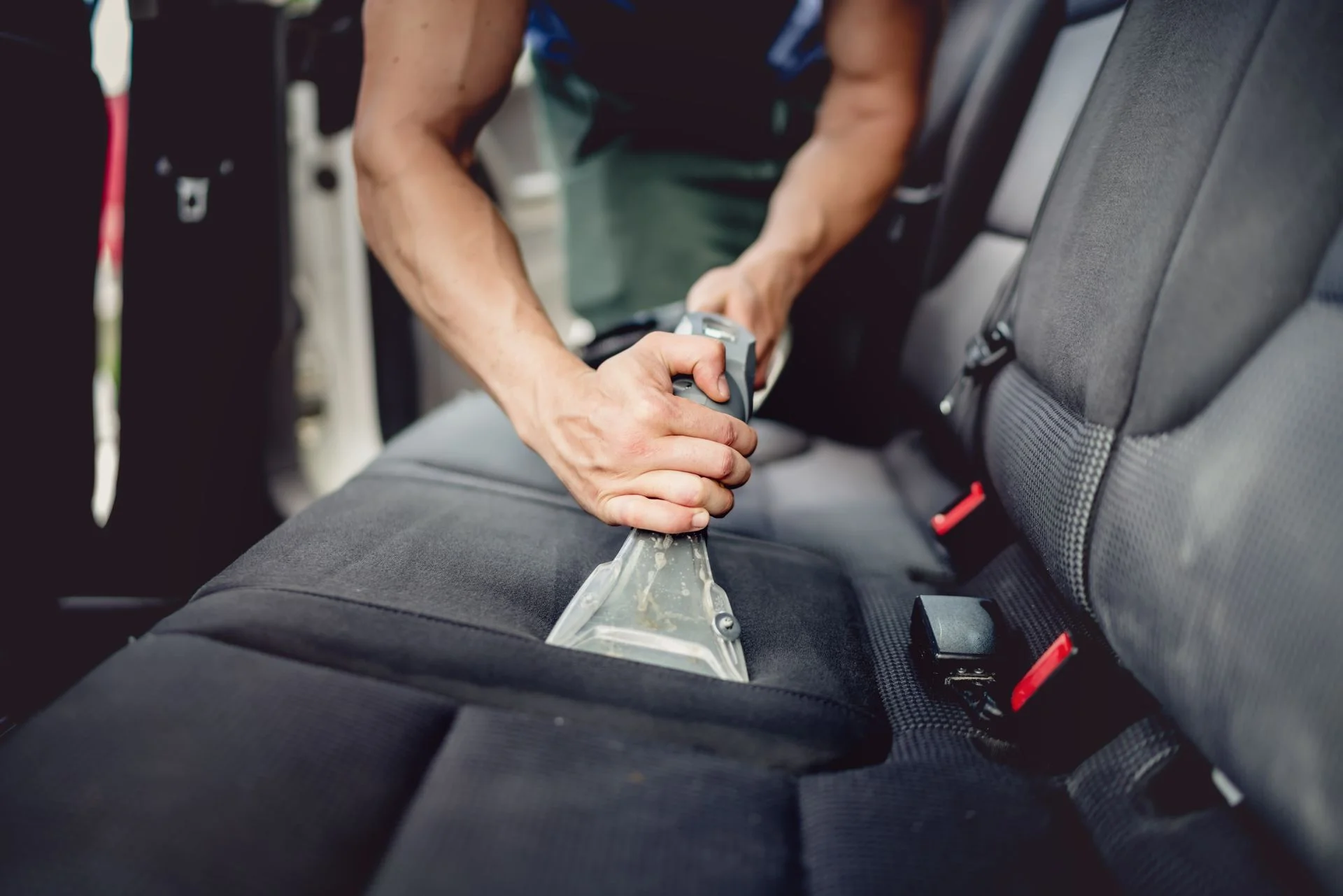Person using upholstery cleaner on car seat interior