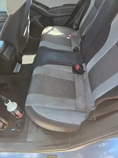 Car interior rear seats with gray and black upholstery, cup holder, and door panel visible