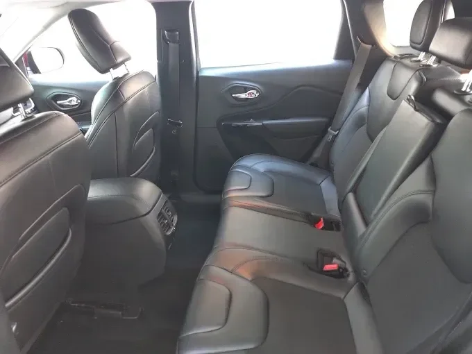 Interior view of vehicle showing black leather rear seats with red seat belt details