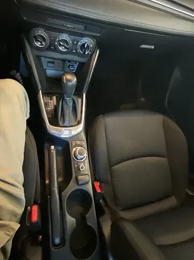 Car interior showing manual transmission shifter, climate controls, and black leather seats